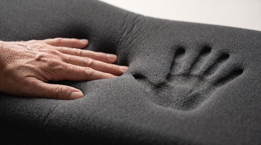 Hand drückt auf den Memory-Schaum